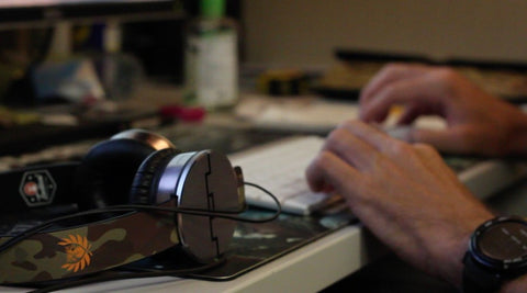 headphones laying on a desk near hands typing at a keyboard in the background